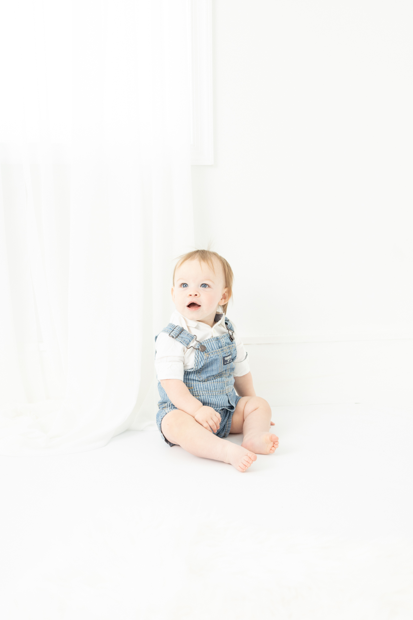 A baby in blue overalls sits in a studio before visiting Ice Cream Shops in Virginia Beach