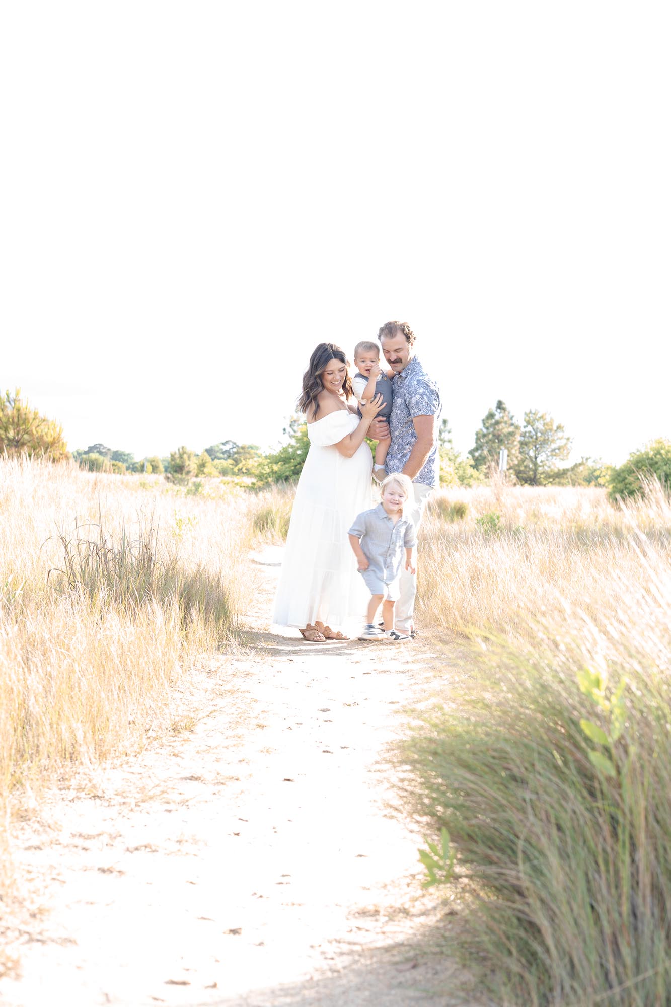 A happy family of 4 play in a beach trail in blue and white