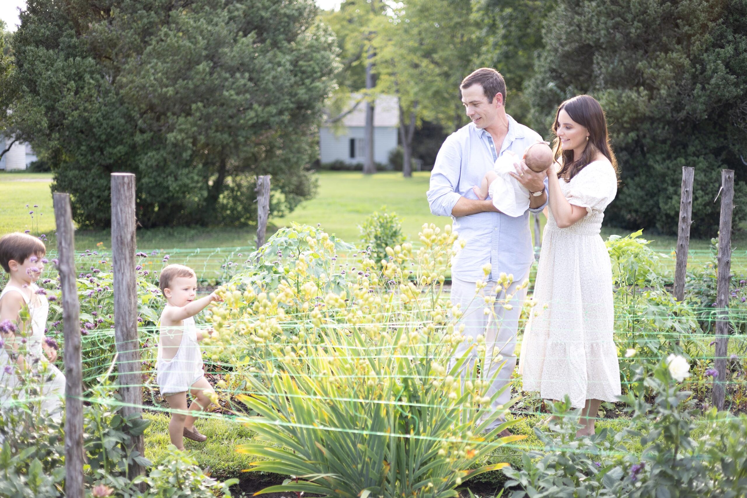 Happy mom and dad explore a garden with their baby and two toddler sons