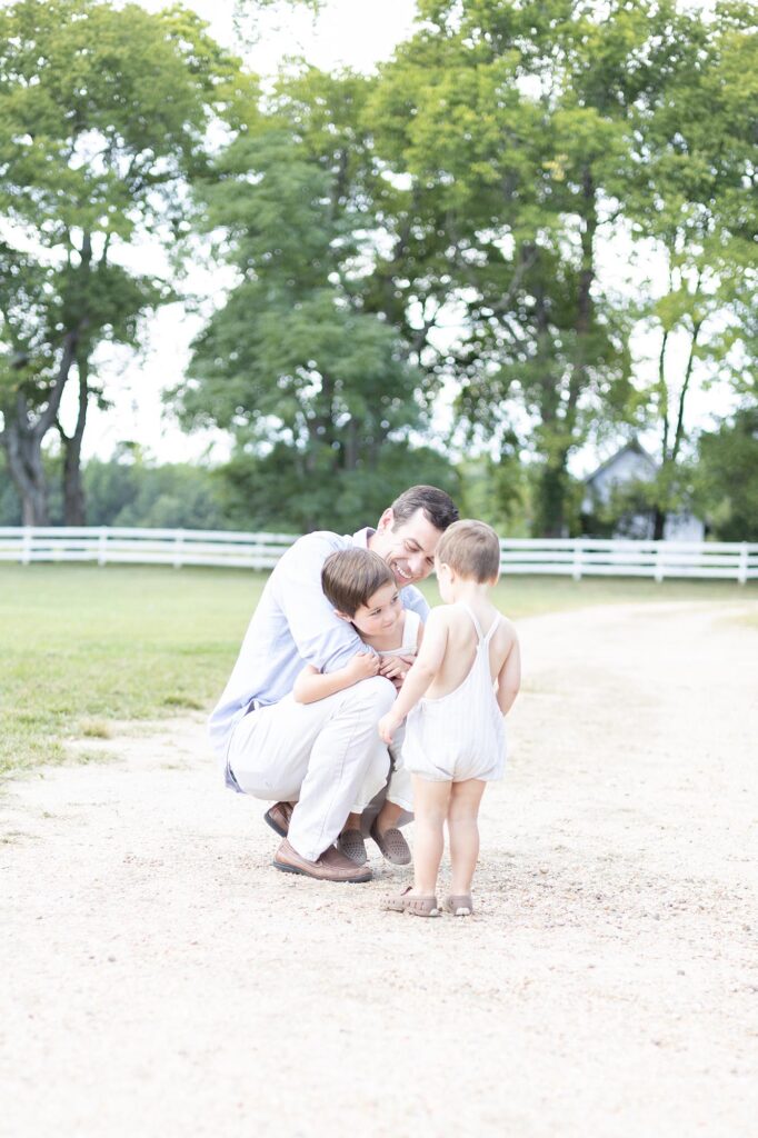 A Dad wearing a Blue linen shirts plays with his two toddler aged sons during a Fall Family Photography session.