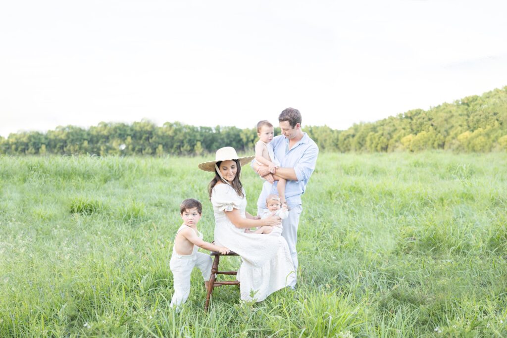 A family of 5 plays together in a field during a family session by Mary Eleanor Photography