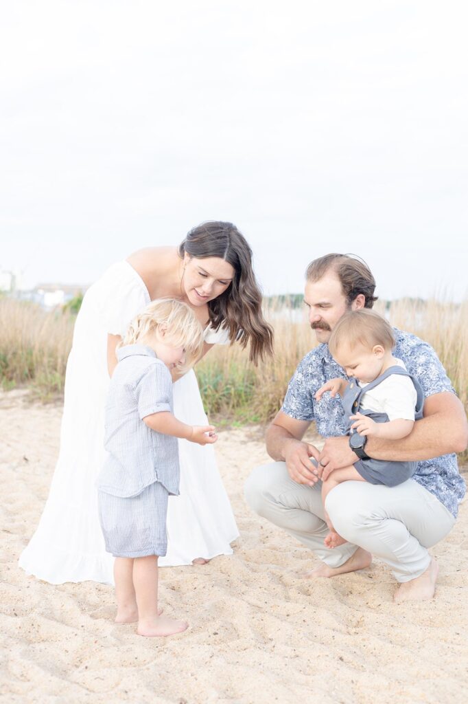 A young family looks at shells found on the beach by Mary Eleanor Photography.