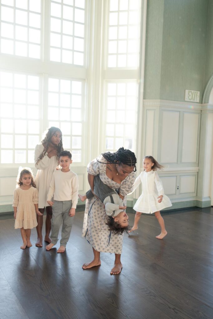 A Mom plays with her youngest child while the other children watch by Mary Eleanor Photography.