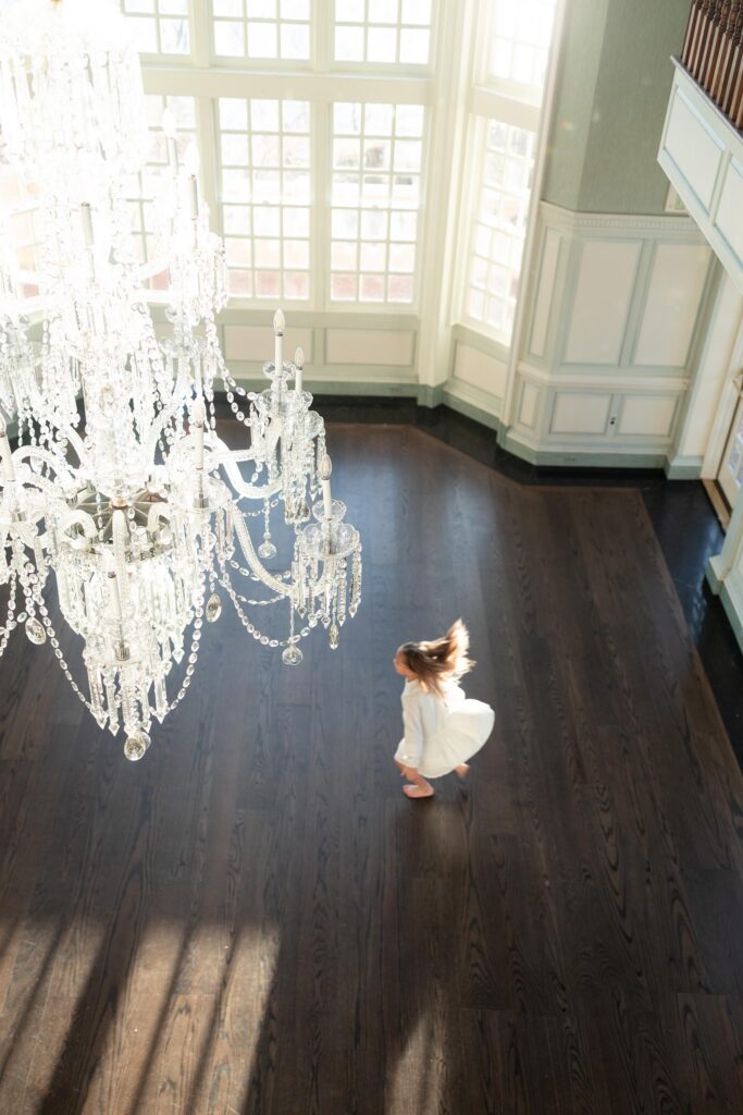 A young girl dances around a large ballroom by Mary Eleanor Photography