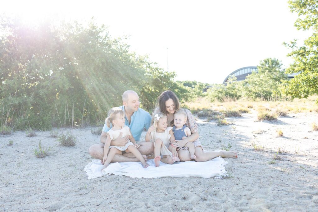 A family snuggles together on a blanket looking at the youngest child before Virginia Beach Fireworks.
