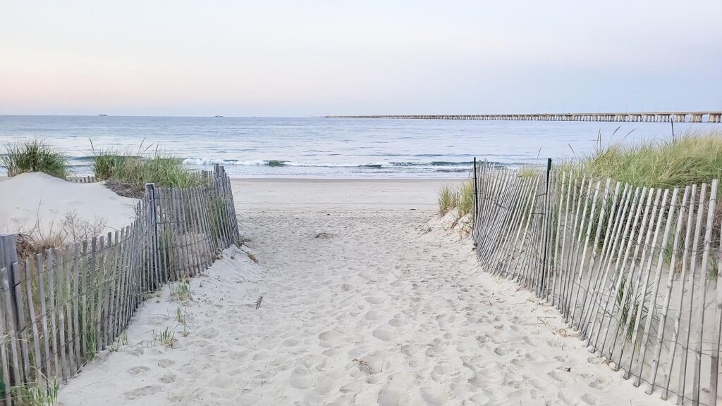 Photograph looking down a beach path to the water in between dunes before Virginia Beach Fireworks.