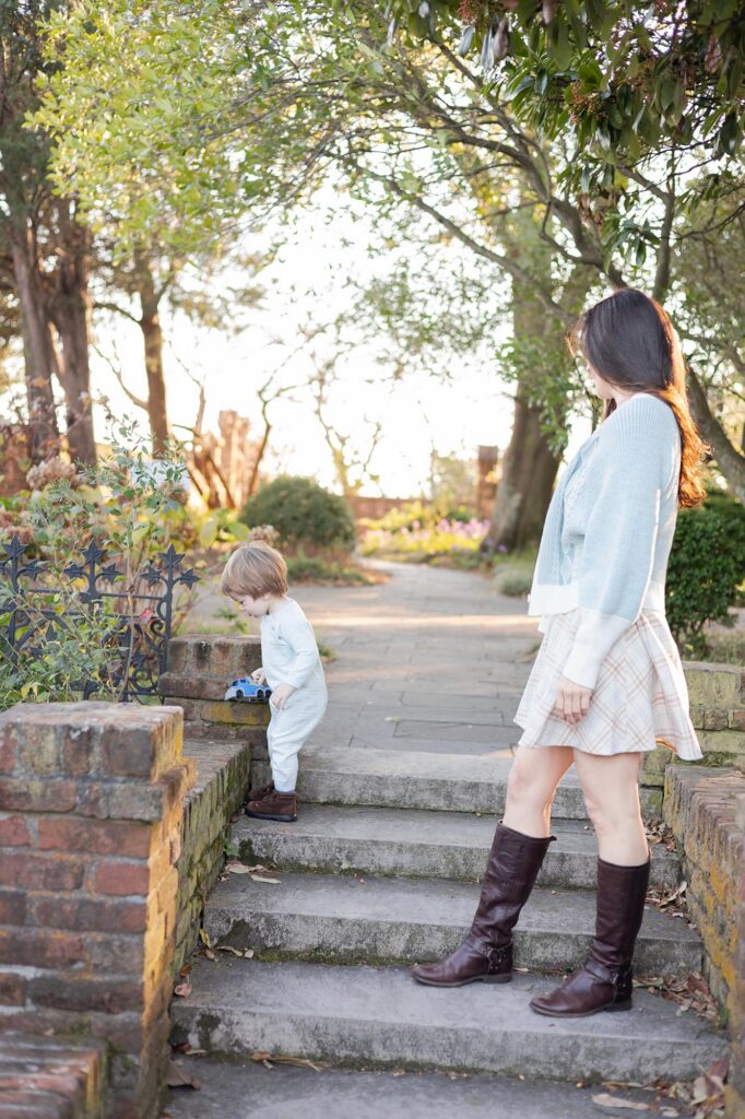 A mom watches her toddler son drive a toy truck along the stairs during Fall Family Photos Virginia Beach.